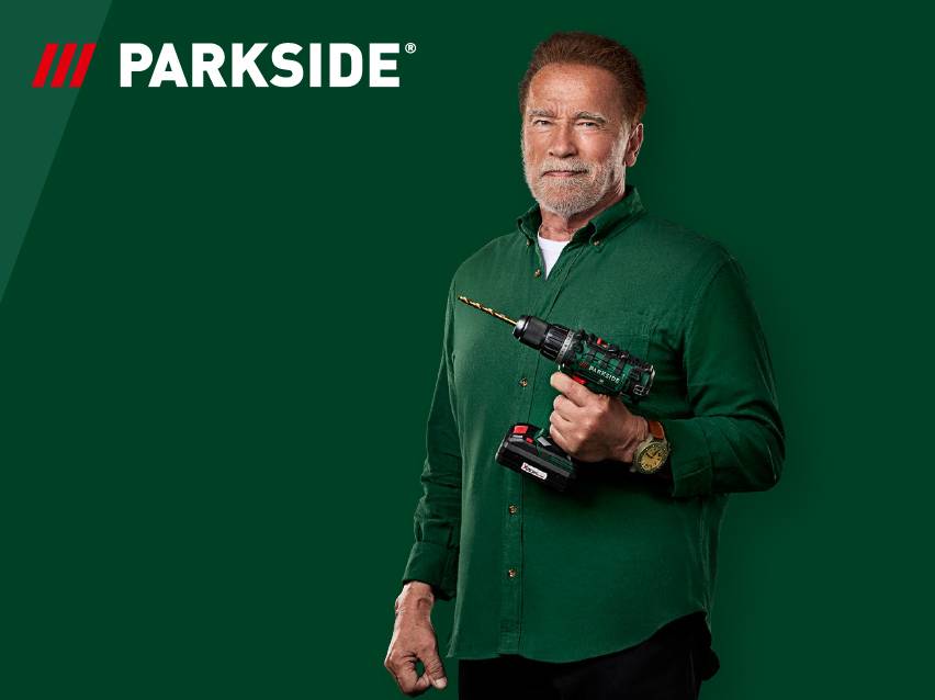 Мъж държи акумулаторна бормашина на зелен фон с лого.