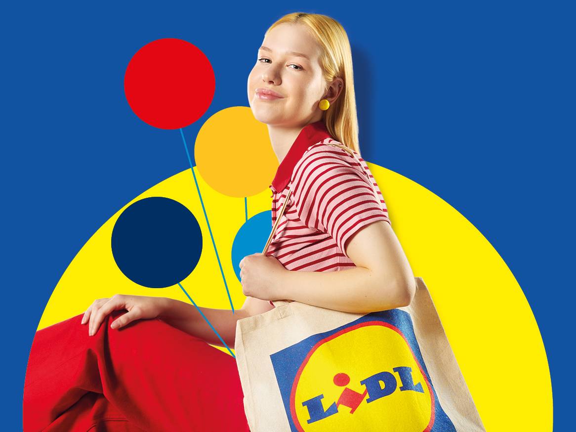 Млада жена с чанта Lidl, облечена в червено-бяла раирана тениска и червени панталони.