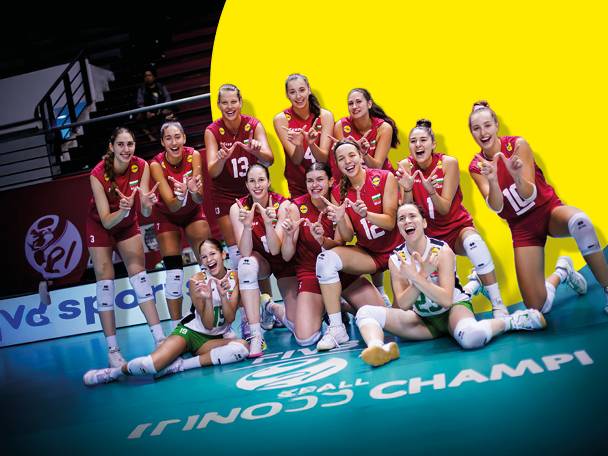 Волейболен отбор от жени в червени и зелени екипи, позиращи на игрището.