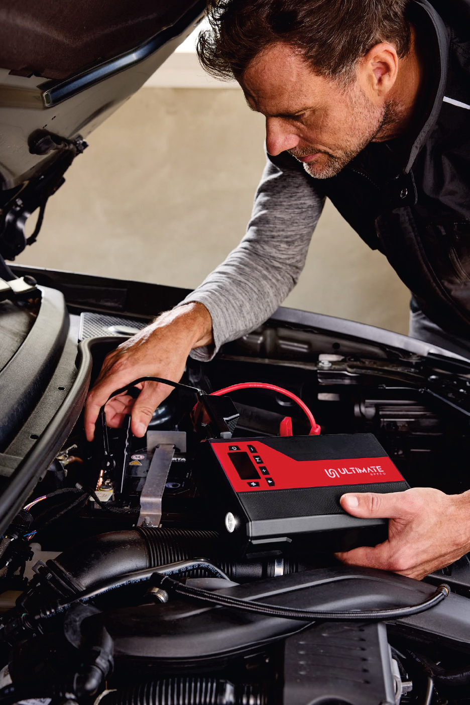 Мъж използва преносим стартер за кола, за да стартира автомобил.