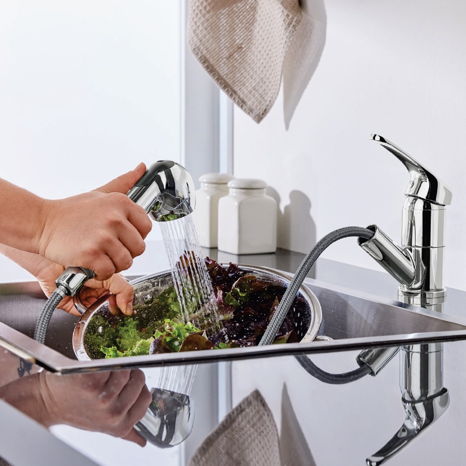 Ръце мият салата в цедка с изтеглящ се кухненски кран над мивка от неръждаема стомана.