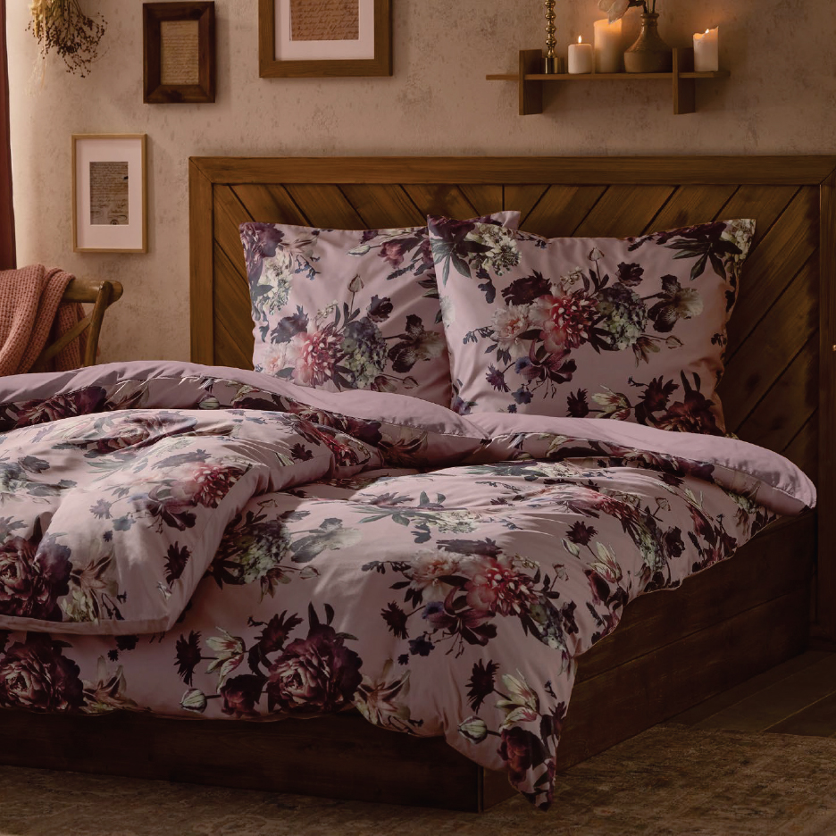 Спално бельо с флорални мотиви в спалня с дървена табла и рамки за картини.