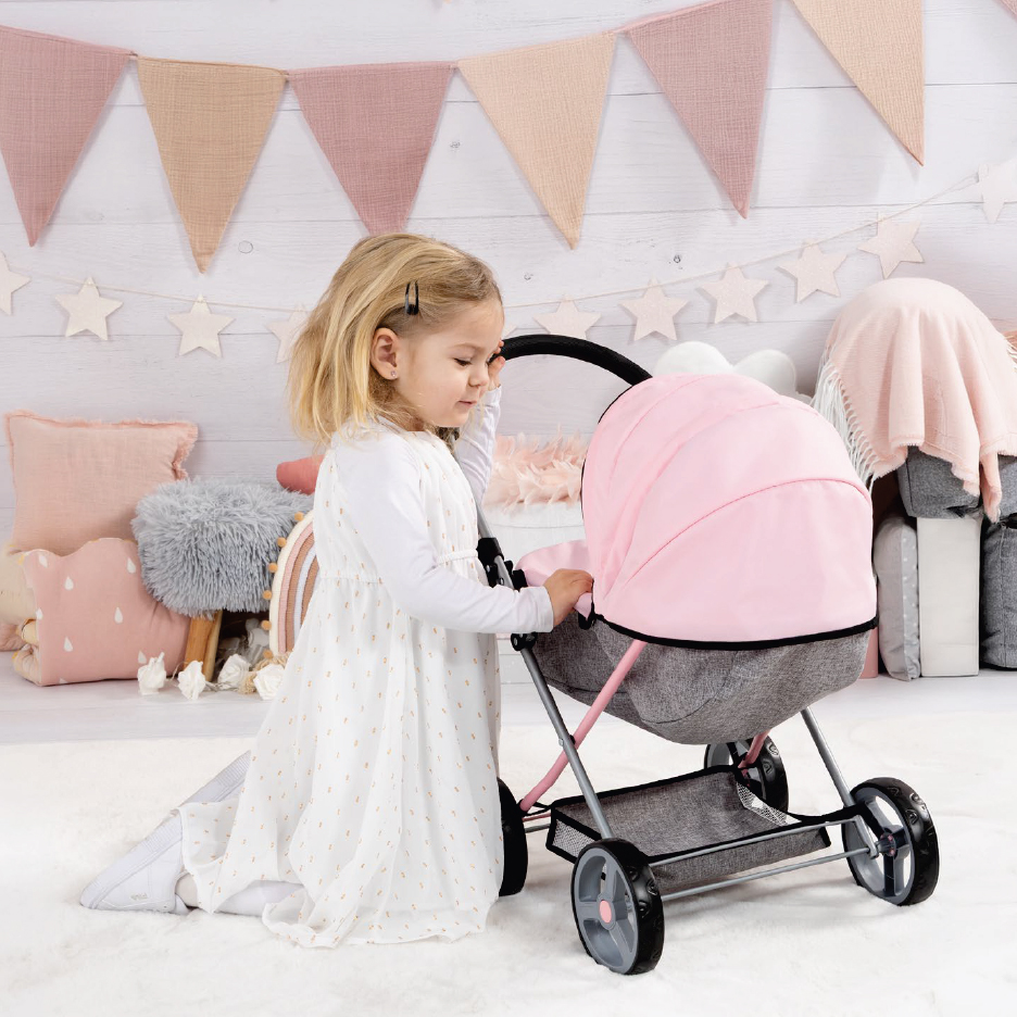Малко момиченце си играе с розова детска количка за кукли.
