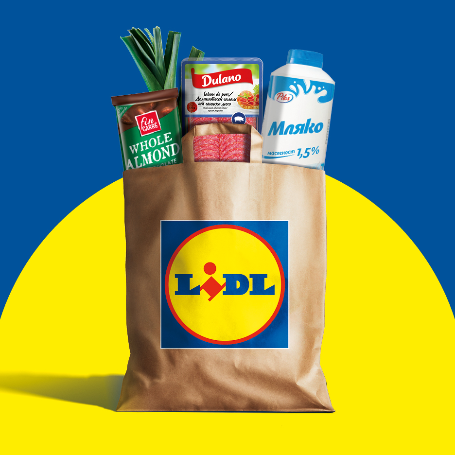 Кафява пазарска чанта с мляко, салам, шоколад и праз на фон в цветовете на украинското знаме.