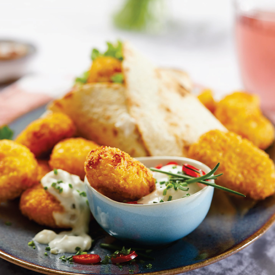 Златни панирани хапки с бял сос, пресен лук и люти чушки, поднесени с питка.