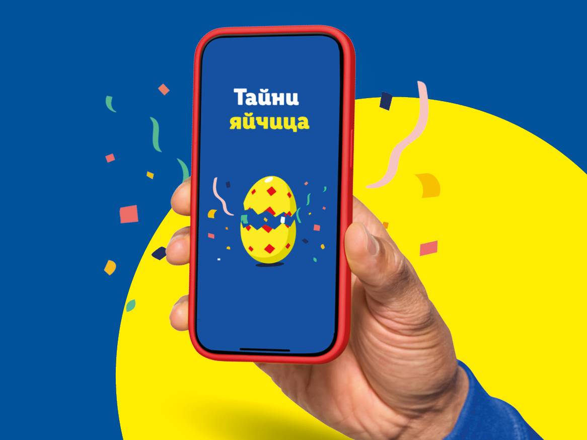 Ръка държи телефон с приложение за Великденски яйца, на син и жълт фон.