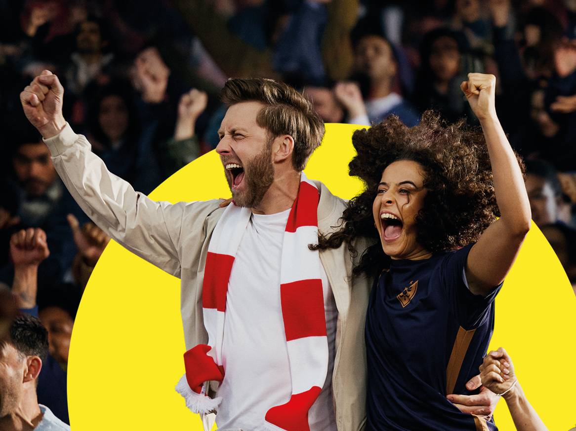 Двама щастливи фенове на футболен мач, облечени в спортни дрехи и шал.